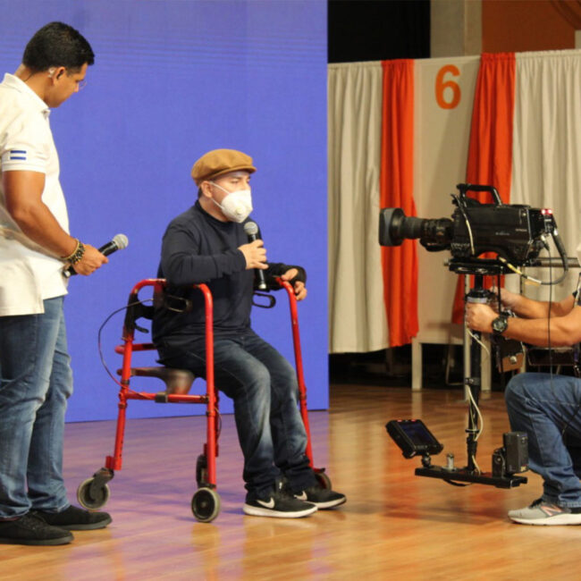 Usuario Teletón que utiliza andadera frente a cámara enviando un mensaje de apoyo a los salvadoreños acompañadp por el presentador Federico Zeledón.